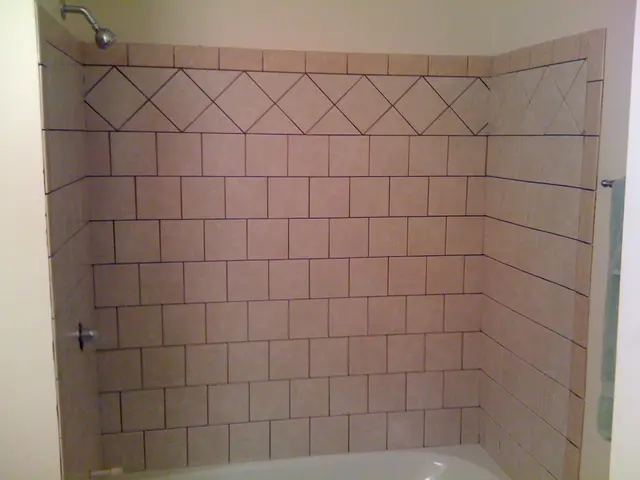 There is a brick wall. On the left side there is a shower and a tap on the wall. At the bottom...