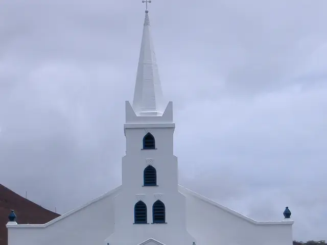 In the center of the image there is a church. At the bottom of the image we can see road. In the...