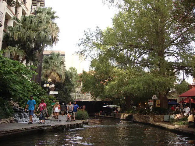 In this image in the center there is water. On the right side there are trees, tents and there are...