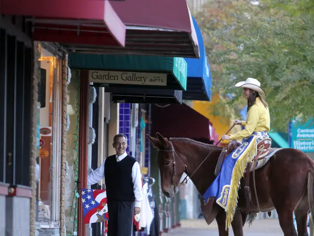 This image consists of stalls on left side and horse on right side. A woman is sitting on horse,...